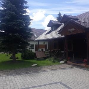 a house with a tree in the yard at Pokoje Gościnne u Huberta in Soblówka