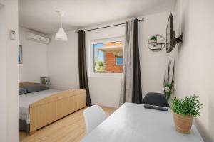 a bedroom with a bed and a table and a window at Frida Rooms and Apartments Vodice in Vodice