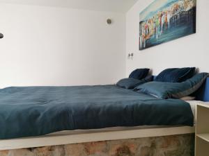 a bed with blue pillows and a painting on the wall at Villa Aura in Milna +16 photos