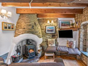 a living room with a stone fireplace and a tv at Ysgubor Ganol in Llanglydwen
