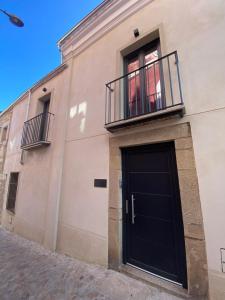 - un bâtiment avec une porte noire et un balcon dans l'établissement Casa Estudio Trujillo, à Trujillo