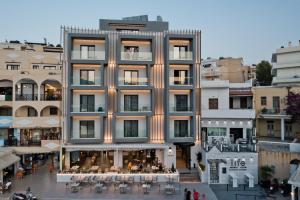 un immeuble d'appartements avec des personnes assises à l'extérieur dans l'établissement Arcus Luxury Suites Karpathos, à Karpathos