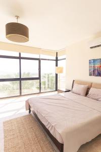 a white bedroom with a large bed and large windows at Little Venice Chalet- Private Villa- Dead Sea Jordan in Sowayma