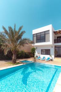 a villa with a swimming pool in front of a house at Little Venice Chalet- Private Villa- Dead Sea Jordan in Sowayma