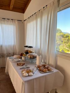 a white table with food on it with a window at Sa Jacca Albergo Rurale in Siniscola