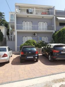 two cars parked in a parking lot in front of a building at Madunić in Podstrana +2 photos