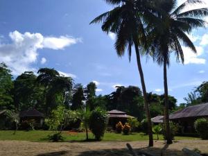 un groupe de personnes debout sous un palmier dans l'établissement Lorenso Cottage, à Manado