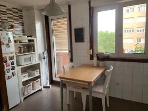 a kitchen with a table and chairs and a refrigerator at Habitación privada para 2 personas a 10 min de la playa in Santander