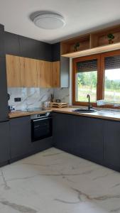 a kitchen with black cabinets and a sink and a window at House_Zoi in Čelinac