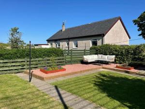 einen Garten mit einer weißen Couch vor einem Haus in der Unterkunft Southend, Mull of Kintyre, Campbeltown in Campbeltown