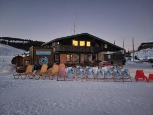 a group of chairs in the snow in front of a lodge at Tinyhouse Postalm in Abtenau