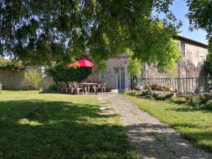 Le gite de la Licorne في Saint-Mihiel: منزل به طاولة وكراسي ومظلة