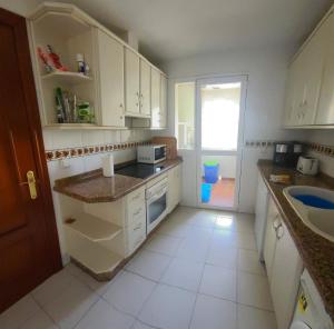 eine kleine Küche mit weißen Schränken und einer Spüle in der Unterkunft 2 bedroom apartment overlooking Mediterranean, 2 outdoor pools in Mijas Costa