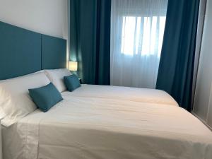 a large bed with two blue pillows on it at VerdeMar 5 (Playa Puerto de Sagunto) in Puerto de Sagunto