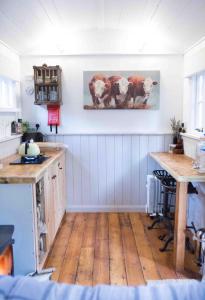 GrimstonにあるKing Nutkin Shepherds Hutの木製の床と壁に牛が描かれたテーブルのあるキッチン
