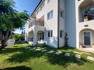 a large white building with a grass yard at Apartment Mia 2 in Rab