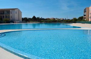 a large swimming pool with blue water at Studio dans résidence, piscine lagon, tennis et aire de jeux in Fréjus