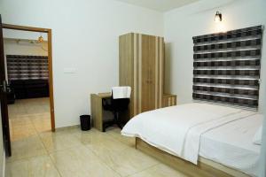 エルナクラムにあるCrystal Villa Suite1 Ground floorの大きな白いベッドと机のある寝室