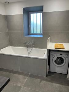 a bathroom with a tub and a washing machine at Le Mas d'Archas Montélimar Sud in Allan