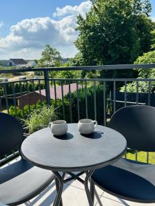 a table with two cups and two chairs on a balcony at Velobaltica apartmenty in Wisełka