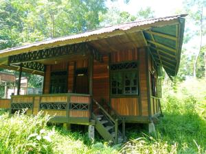 a small wooden house with a porch in the grass at Lorenso Cottage in Manado