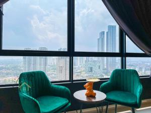 dwa zielone krzesła i stół przed oknem w obiekcie Twin Tower Residence by Nest Home【5 mins walk to CIQ】 w mieście Johor Bahru