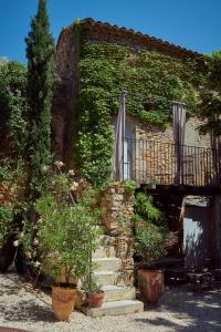 Les Sardines aux Yeux Bleus Chambres d'Hôtes في Aigaliers: مبنى حجري عليه درج ونباتات