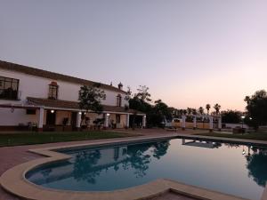 una grande piscina di fronte a un edificio di Cortijo la amazona a Siviglia Altre 18 foto