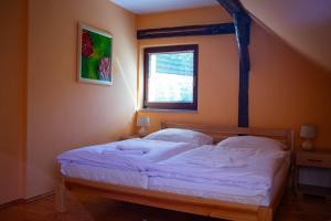 a bedroom with a bed with white sheets and a window at Apartmán NIKA in Levoča