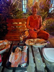 a woman sitting on a bench with two trays of food at Eastwind Surf Camp in Arugam Bay