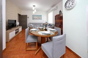 a dining room with a table and chairs and a clock at Apartment Sunny Terrace in Bibinje