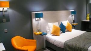 Schlafzimmer mit einem Bett mit gelben und blauen Kissen in der Unterkunft Hôtel L'Européen in Tarbes