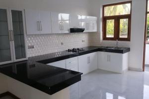 uma cozinha com armários brancos e bancadas pretas em Luxury 2BR Apartment in Ratmalana em Ratmalana South