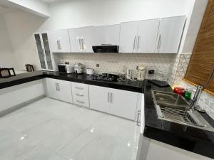 Luxury 2BR Apartment in Ratmalana في Ratmalana South: مطبخ مع خزائن بيضاء وقمم منضدة سوداء