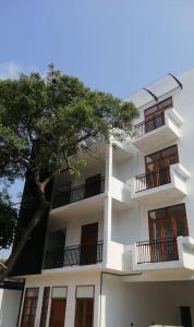 a white building with a tree in front of it at Luxury 2BR Apartment in Ratmalana in Ratmalana South