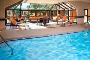 a swimming pool with chairs and a table in a building at Courtyard Toledo Airport Holland in Holland