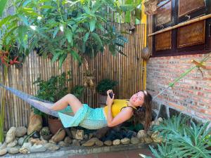 a woman laying on a hammock in a garden at Homestay Da Nang Full House in Danang