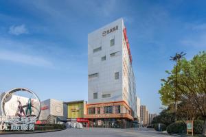 un grand bâtiment blanc avec un panneau sur celui-ci dans l'établissement Minimax Hotel Shanghai Songjiang, à Songjiang