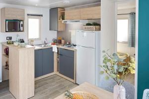 eine Küche mit einem weißen Kühlschrank und einem Tisch in der Unterkunft Camping Paradis Le Grand' R in La Faute-sur-Mer
