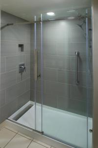 a shower with a glass door in a bathroom at Marriott East Lansing at University Place in Lansing