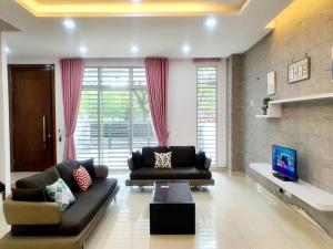 uma sala de estar com dois sofás e uma televisão em MODERN STYLISH 2STOREY HOUSE 8PAX@ALMA NEAR JUSCO em Bukit Mertajam