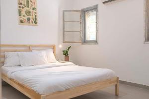 a white bedroom with a bed with white sheets and a window at מקום לנשום בית אירוח in Sheʼar Yashuv