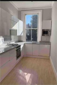 uma grande cozinha com armários brancos e uma janela em Lovely 2-beds flat in the heart of Knightsbridge em Londres
