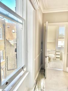 uma casa de banho com uma janela e um WC. em Lovely 2-beds flat in the heart of Knightsbridge em Londres