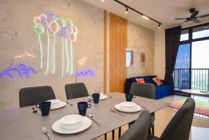 een eetkamer met een tafel met stoelen en een muur met een schilderij bij Twin Tower Residence by Nest Home【5 mins walk to CIQ】 in Johor Bahru