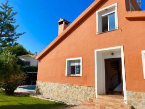 a orange house with a door and a tree at Chalet con piscina cerca playa in La Venteta