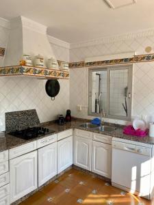 a kitchen with white cabinets and a sink at Chalet con piscina cerca playa in La Venteta