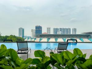 Dos sillas frente a una piscina con una ciudad. en Twin Tower Residence by Nest Home【5 mins walk to CIQ】, en Johor Bahru