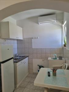 a kitchen with a white refrigerator and a table at APARTMANI ALEN in Dinjiška