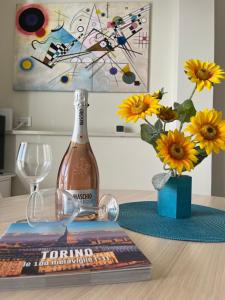 a bottle of wine on a table with a book and flowers at Attico Gabri - Appartamento con terrazzo panoramico vicino al Centro in Turin